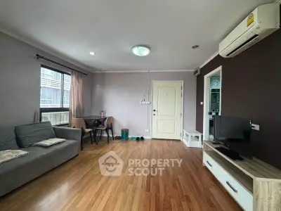 Spacious living room with modern decor and natural light, featuring wooden flooring and a cozy seating area.