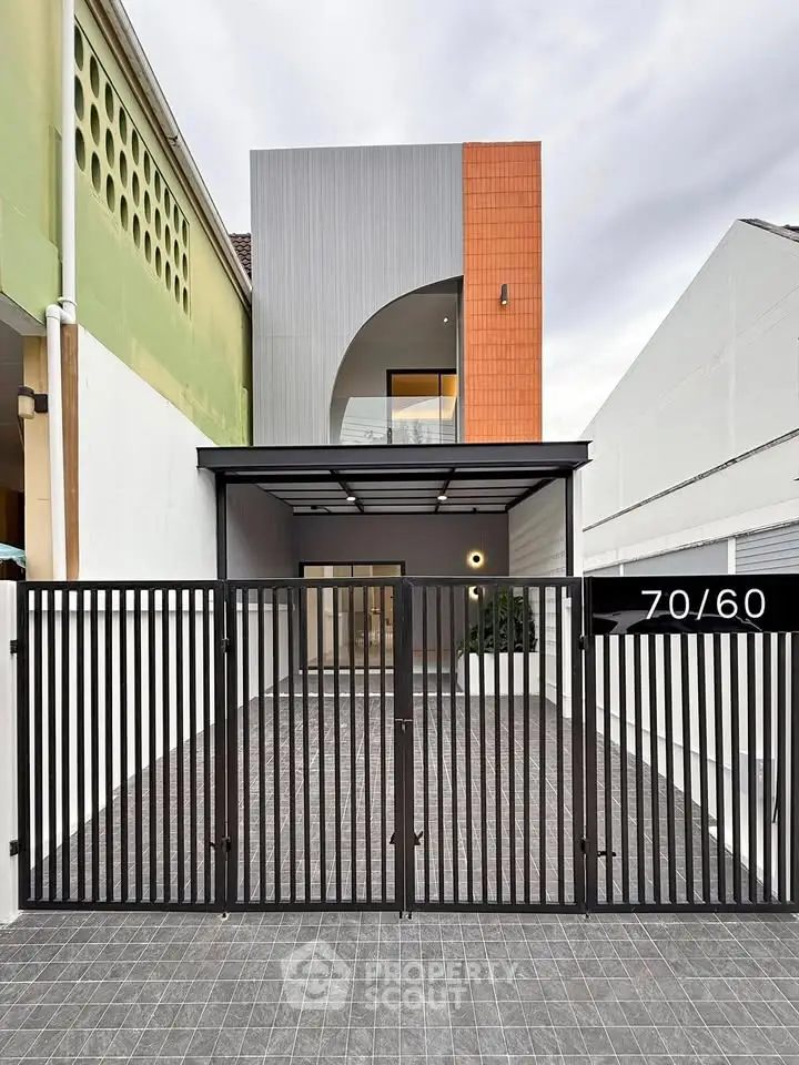 Modern minimalist house exterior with gated entrance and unique architectural design.