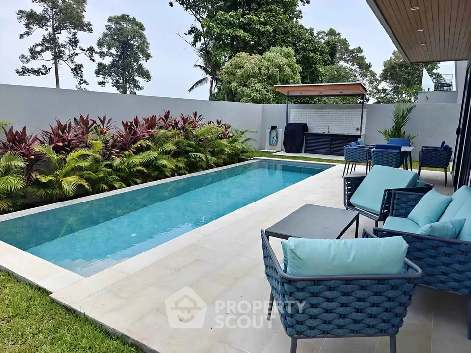 Luxurious outdoor pool area with modern seating and lush greenery, perfect for relaxation and entertainment.
