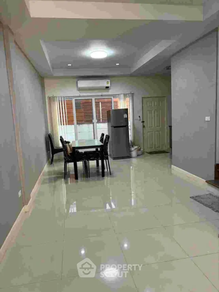 Spacious dining area with modern decor and natural light, featuring sleek furniture and a contemporary fridge.