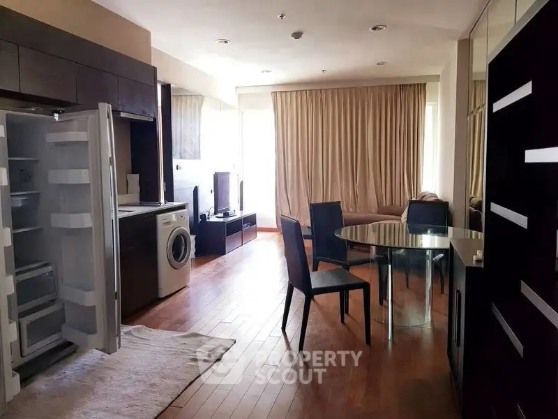Modern apartment interior with open kitchen and living area featuring hardwood floors and natural light.