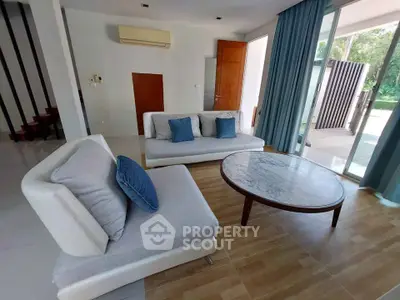 Spacious living room with modern furniture and large windows opening to a garden view.