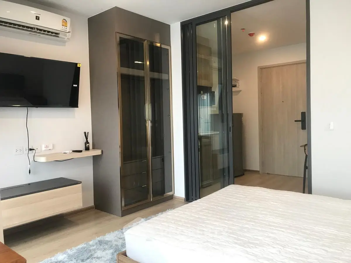 Modern bedroom with sleek design, featuring a wall-mounted TV and glass cabinet.