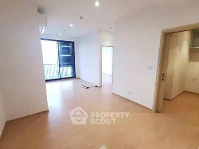 Spacious modern apartment with wooden flooring and large windows for natural light.