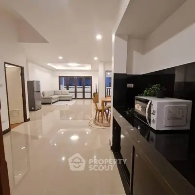 Spacious open-plan living room with modern kitchen and sleek tile flooring.