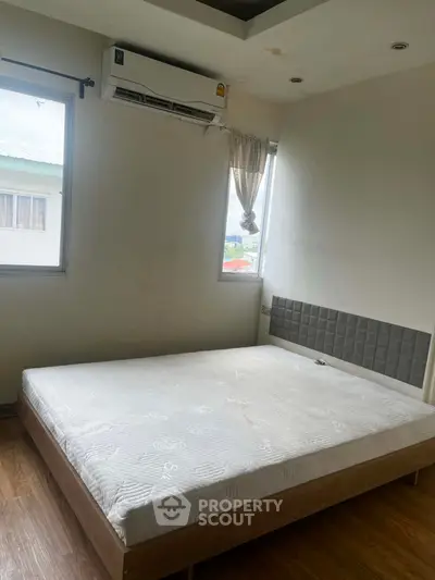 Spacious bedroom with large windows and modern air conditioning unit, perfect for comfort and relaxation.