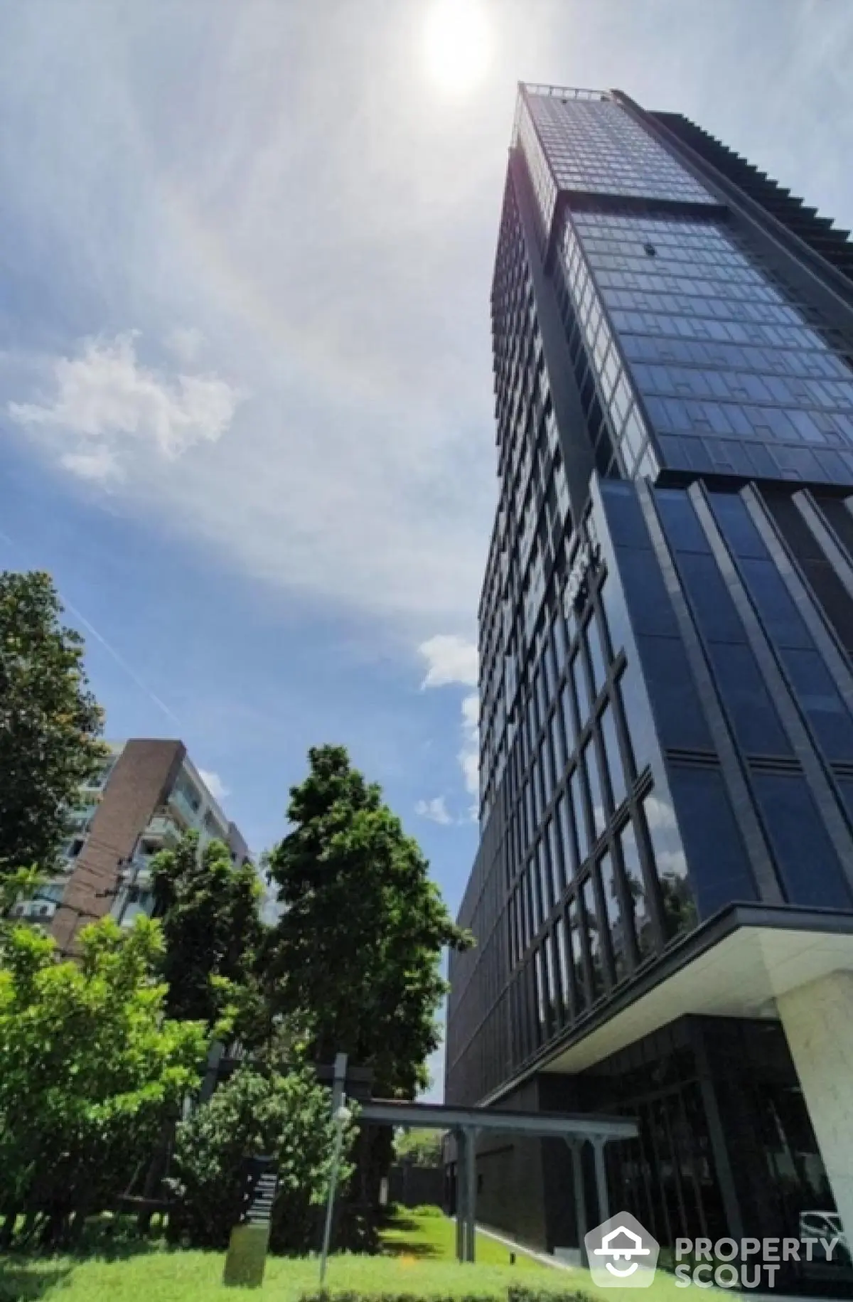 Stunning modern high-rise building with lush green surroundings and clear blue sky