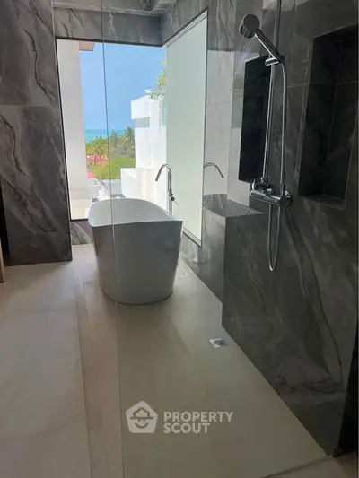 Luxurious bathroom with freestanding tub and ocean view, featuring elegant marble design.