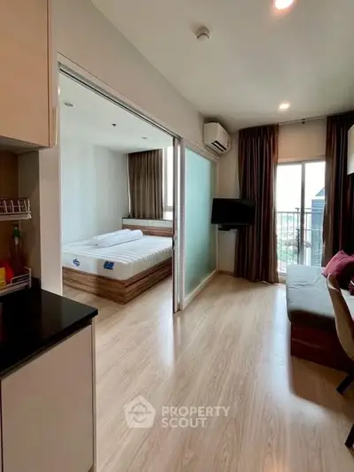 Modern apartment with open layout, featuring a cozy living area and a bright bedroom with balcony access.
