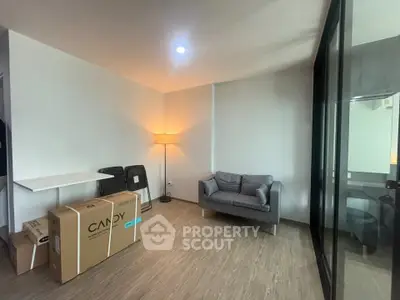 Modern living room with cozy sofa and floor lamp, featuring wooden flooring and glass partition.