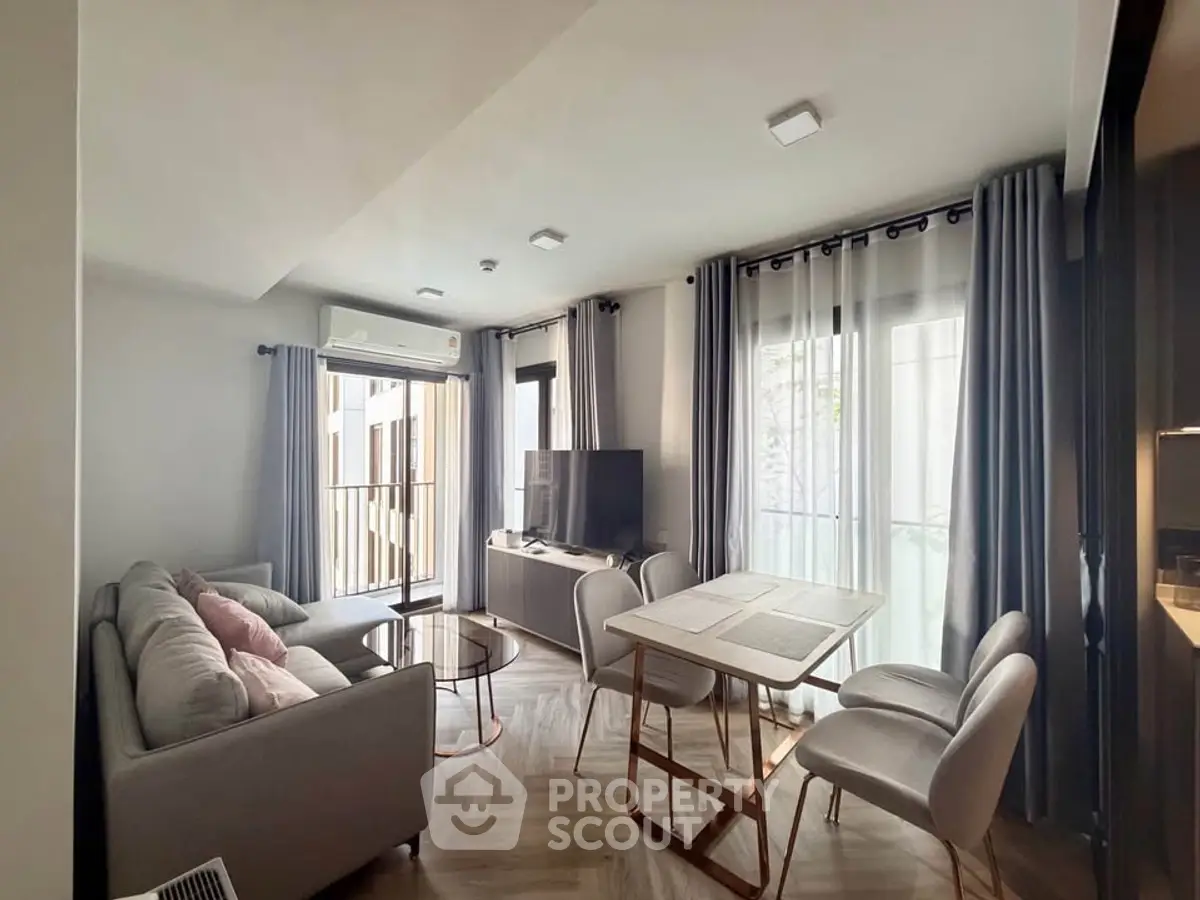 Modern living room with cozy sofa, dining table, and balcony access in a stylish apartment.