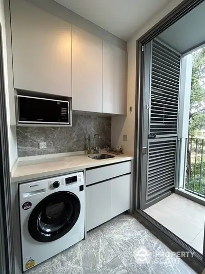 Modern kitchen with washing machine and balcony view in stylish apartment