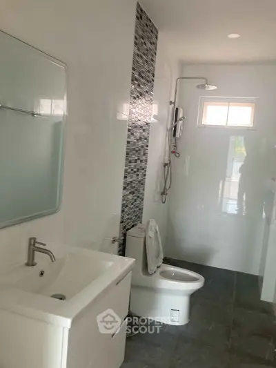 Modern bathroom with sleek fixtures and stylish tile accents, featuring a shower and vanity.