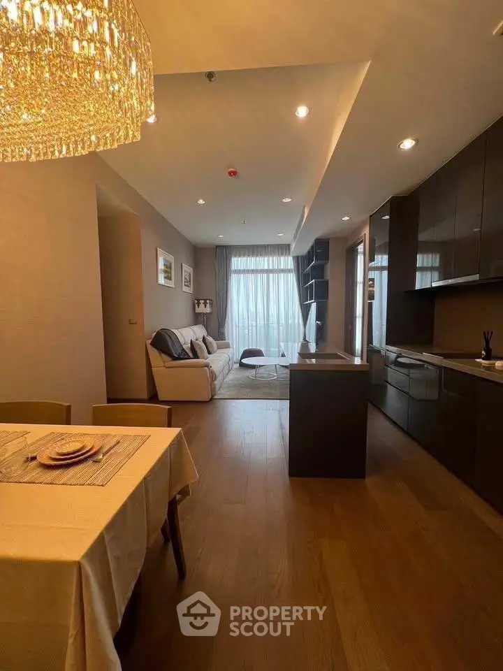 Modern open-layout kitchen and living room with elegant lighting and wooden flooring.
