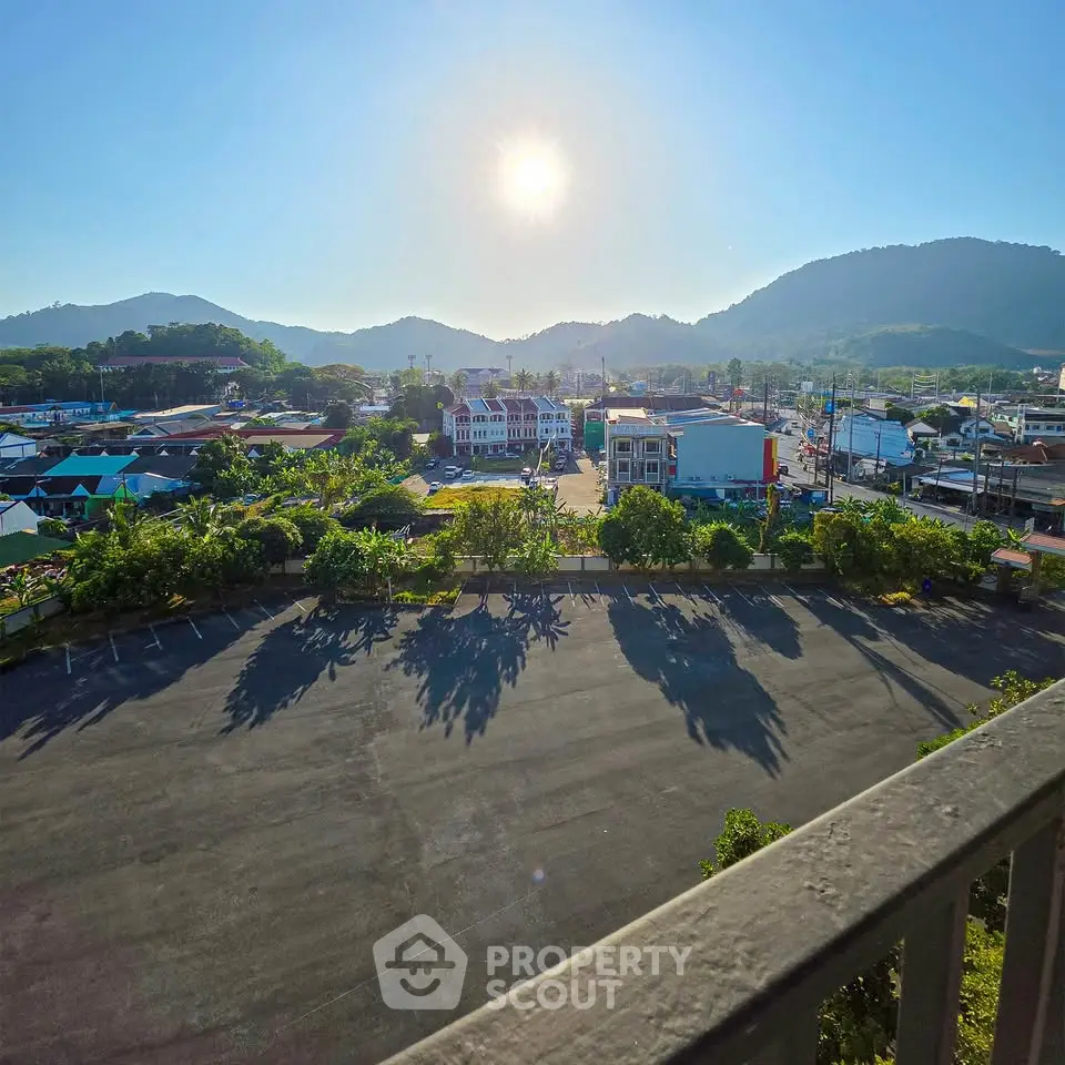 Scenic view from balcony overlooking cityscape and mountains under clear blue sky.