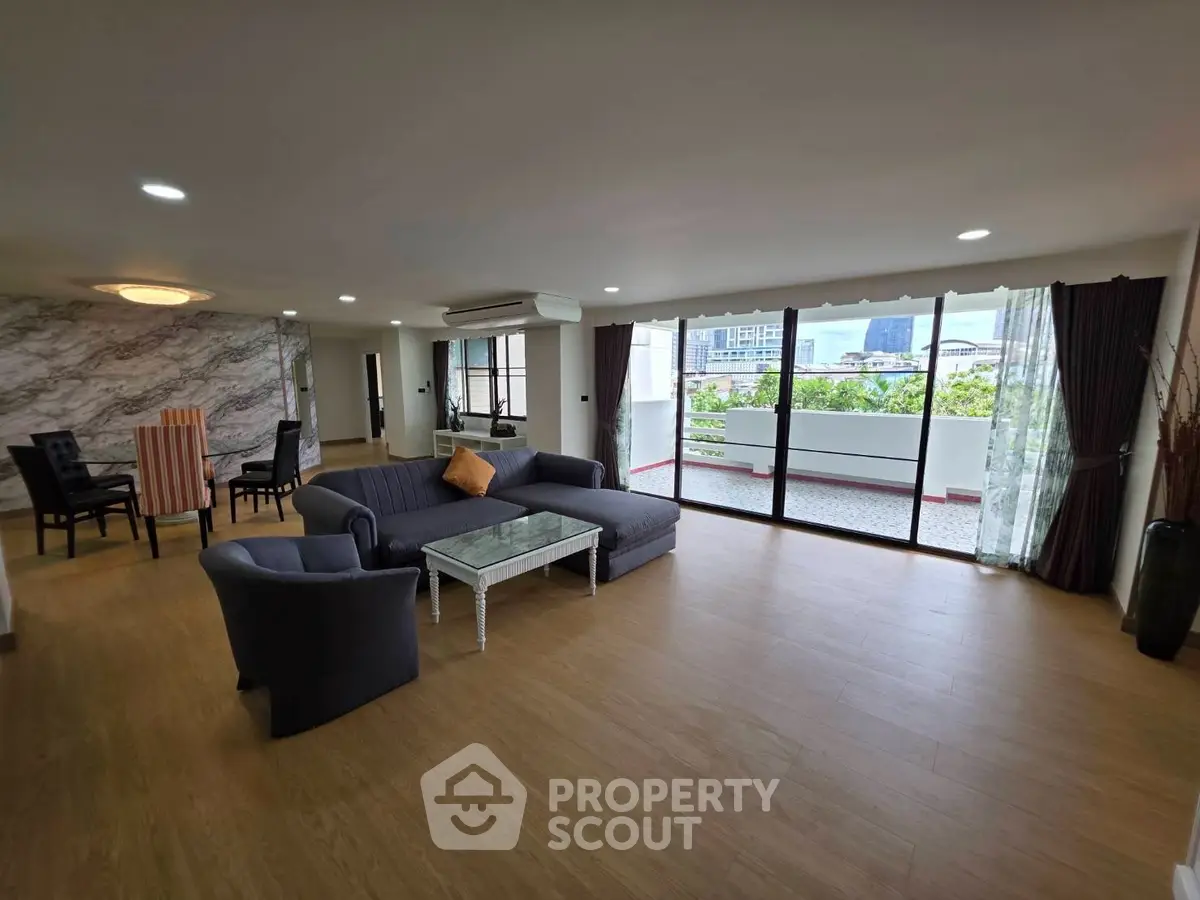 Spacious living room with modern decor and large balcony offering city views