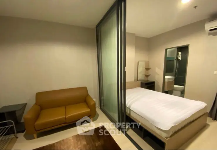 Modern studio apartment with cozy living area and glass partitioned bedroom.