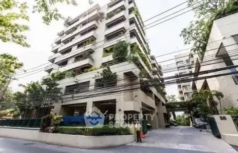Modern apartment building with lush greenery and spacious balconies in urban setting.