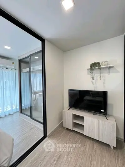Modern living room with sleek TV stand and glass partition, bright and airy ambiance.