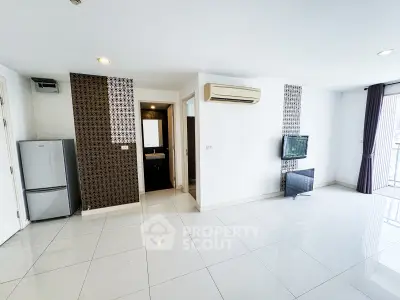 Spacious modern living room with sleek tile flooring and wall-mounted TV, featuring a compact kitchen area.