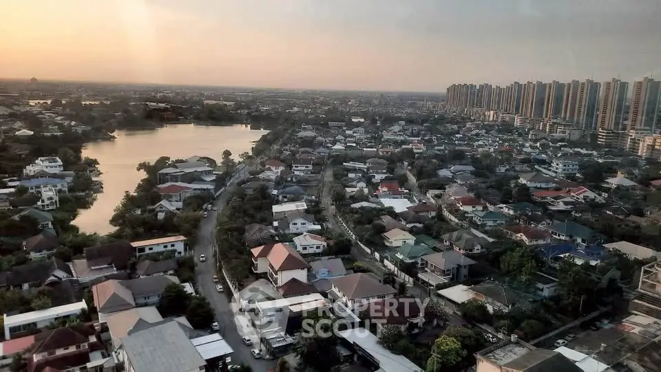 Stunning aerial view of suburban neighborhood with lake and city skyline at sunset.