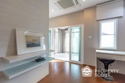 Spacious and well-lit living room with modern floating TV console, sleek flooring, and large windows leading to a sunny balcony.