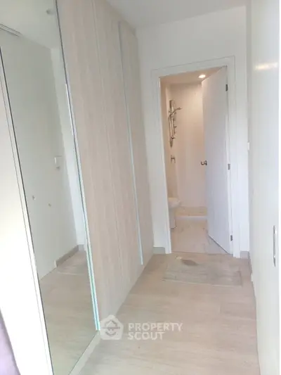 Modern hallway with wooden flooring leading to a sleek bathroom