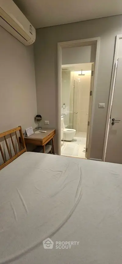 Cozy bedroom with ensuite bathroom and wooden furniture, perfect for comfortable living.