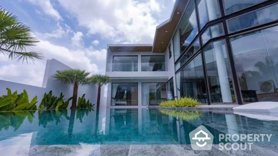 Luxurious modern villa with stunning glass facade and private pool under blue skies.