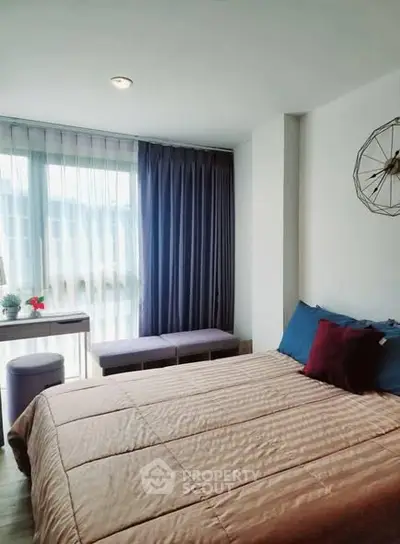 Cozy bedroom with modern decor and natural light through large window.