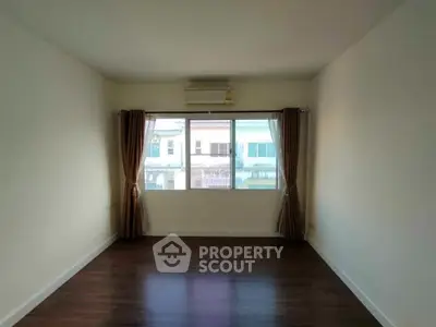 Spacious empty room with large window and wooden flooring, ideal for customization.