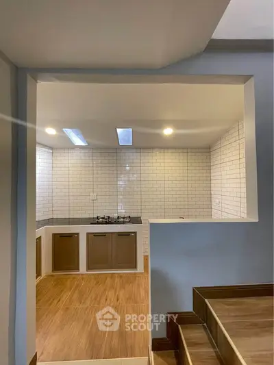 Modern kitchen with wooden cabinets and white subway tiles, featuring skylights for natural lighting.