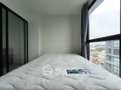 Modern bedroom with large windows offering city views, featuring a comfortable mattress and minimalist design.