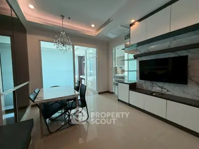 Modern dining area with elegant chandelier and built-in TV unit in a stylish apartment.