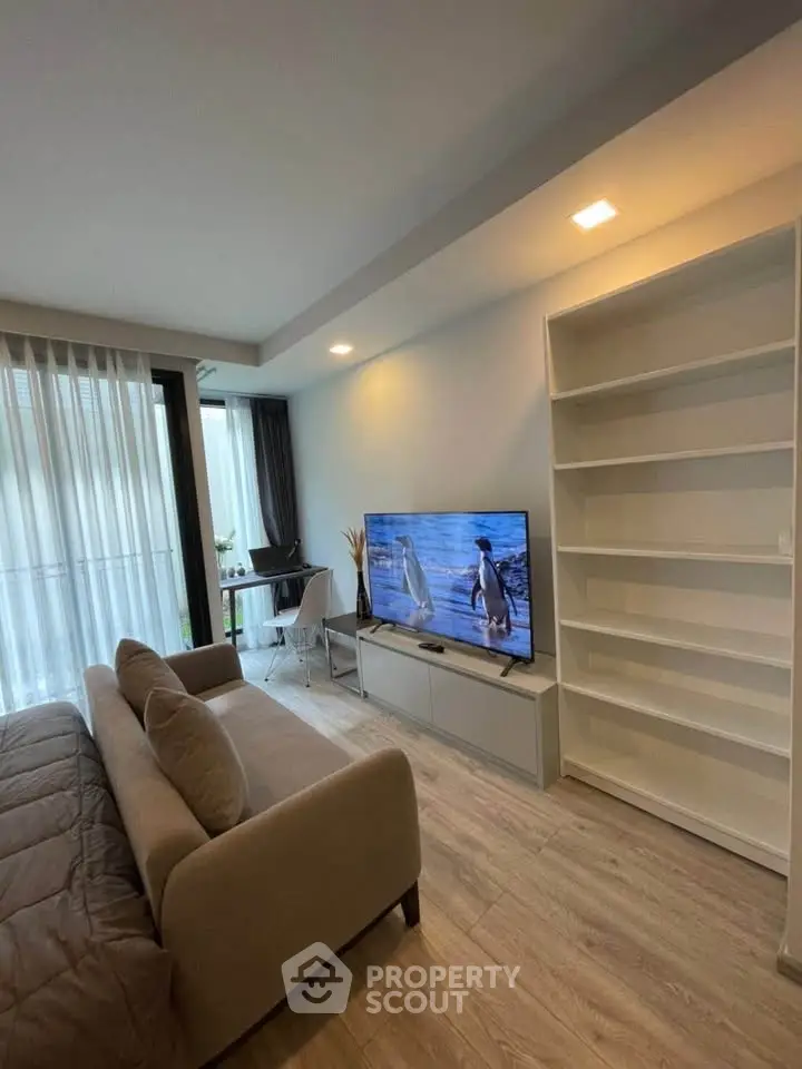 Modern living room with sleek TV setup and cozy sofa, featuring floor-to-ceiling windows.