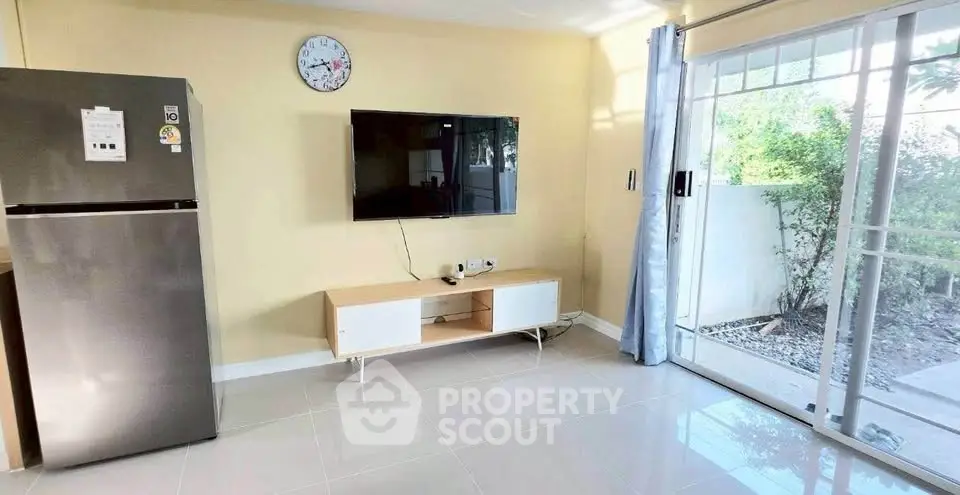 Bright living room with modern TV setup and sliding glass doors to garden