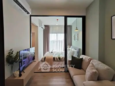 Modern apartment with cozy living room and stylish bedroom separated by glass wall.