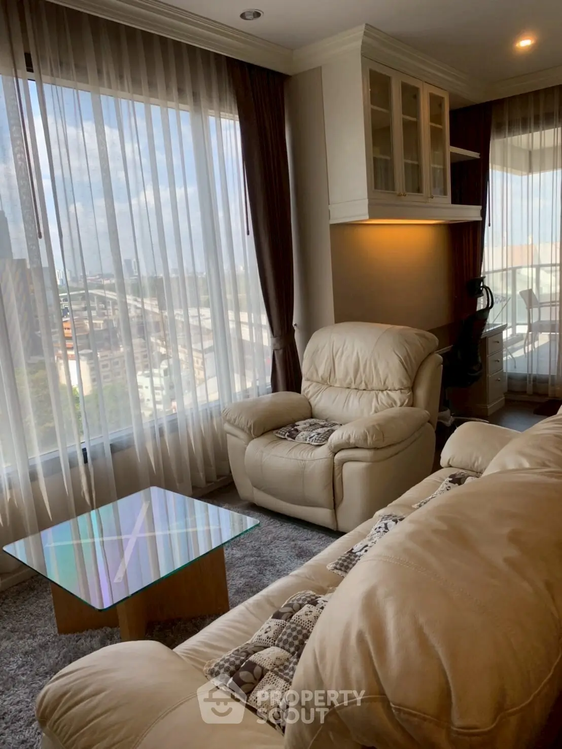 Luxurious living room with plush leather sofas and panoramic city view.