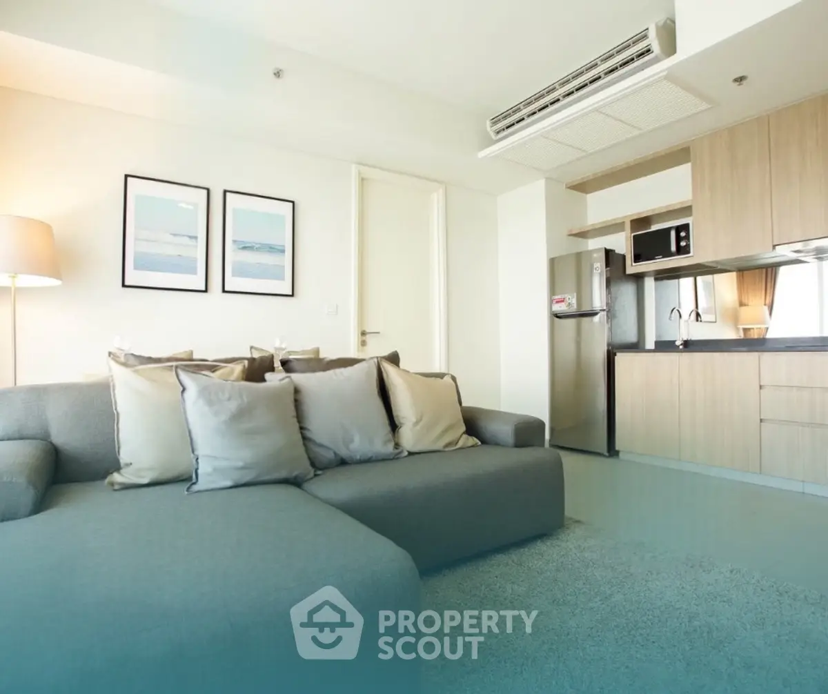 Modern living room with sleek kitchen, cozy sofa, and stylish decor in open layout apartment.