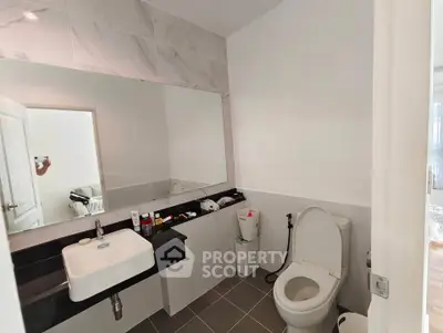 Modern bathroom with sleek fixtures and large mirror in a bright setting.