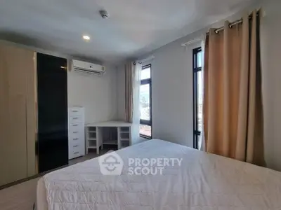 Spacious bedroom with modern furnishings and large windows offering city views.