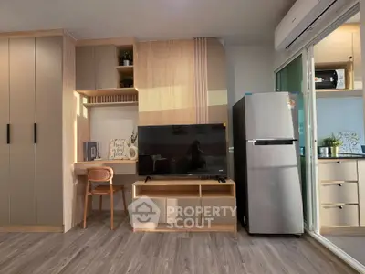 Modern living room with sleek furniture, built-in storage, and stainless steel fridge in a stylish apartment.