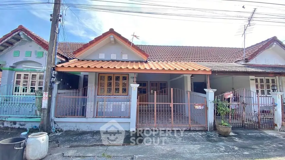 Charming single-story home with tiled roof and gated front yard in a serene neighborhood.
