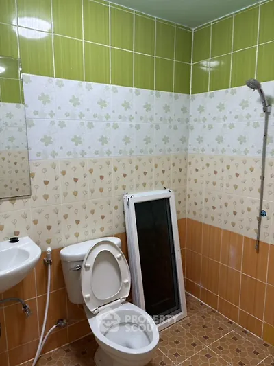 Compact bathroom with colorful tiles and essential fixtures