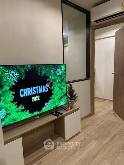 Modern living room with wooden flooring and TV displaying Christmas 2022 theme.