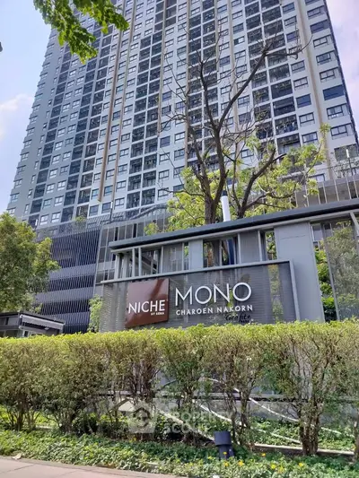 Modern high-rise condominium with lush greenery and stylish entrance signage.