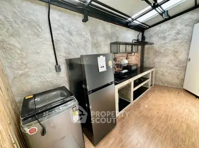 Modern kitchen with sleek appliances and industrial design, featuring a fridge and washing machine.