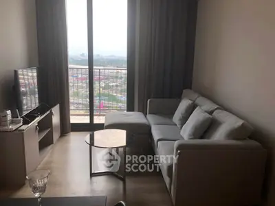Modern living room with a stunning city view from the balcony, featuring a cozy sofa and sleek TV setup.