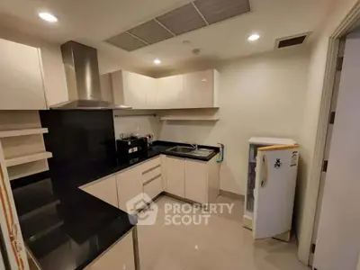 Modern kitchen with sleek cabinetry and black countertops in a contemporary apartment.