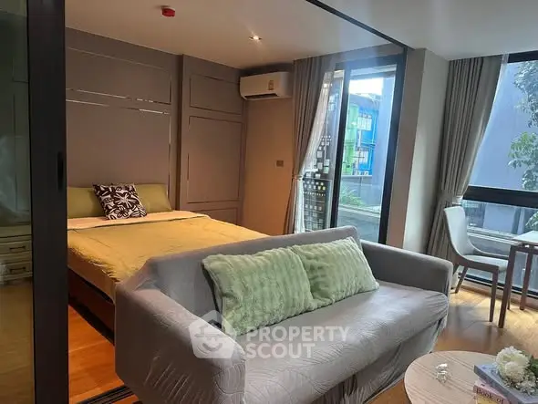 Modern studio apartment with cozy living area and large windows for natural light.